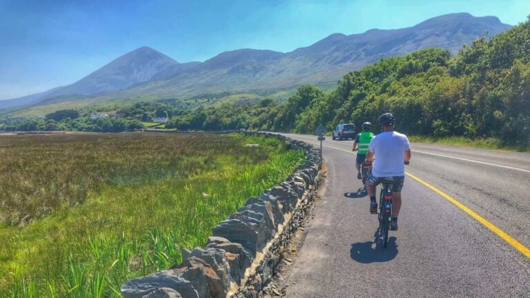 Two cyclists on a country road in County Mayo with mountains ahead