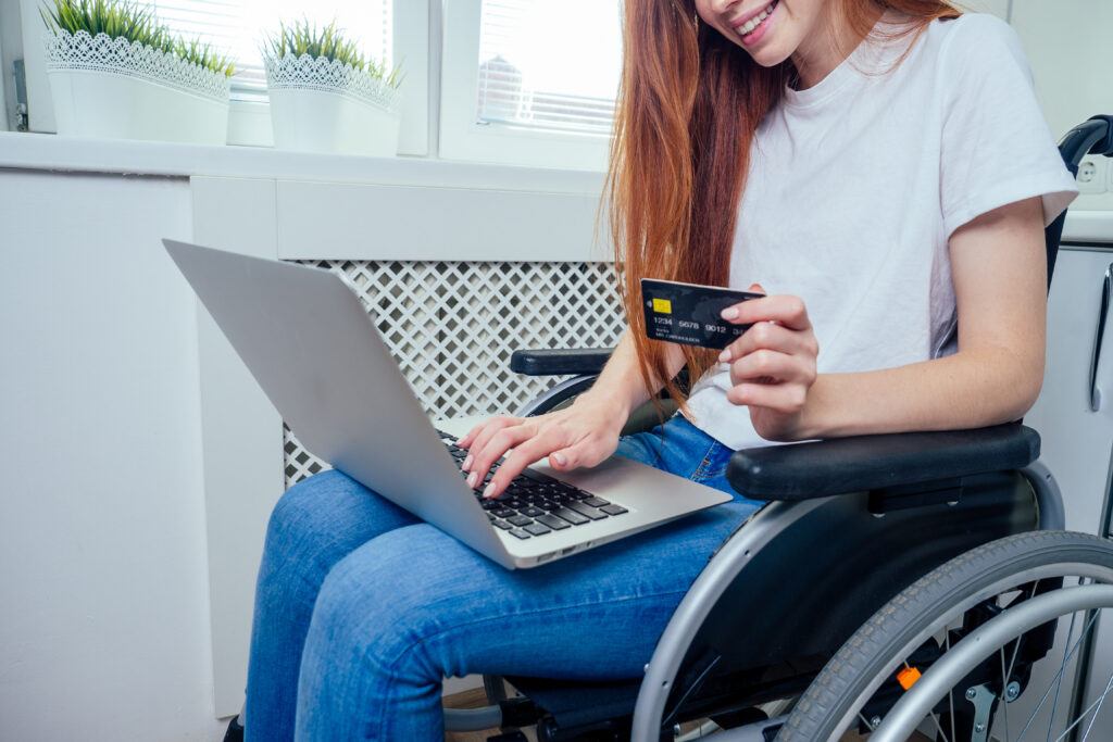 Woman in a wheelchair making an online payment on a laptop at home